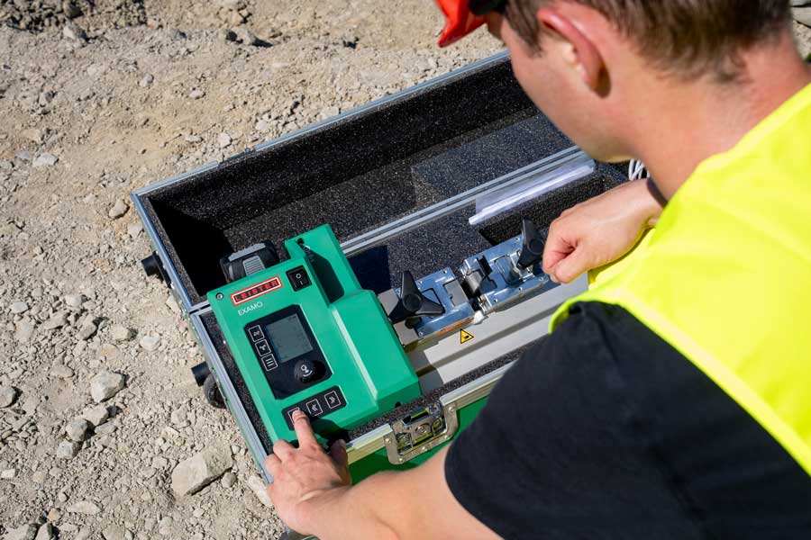 Equipo portátil de ensayo de tracción EXAMO 705-LP a batería en su maleta durante un ensayo de geomembrana en obra